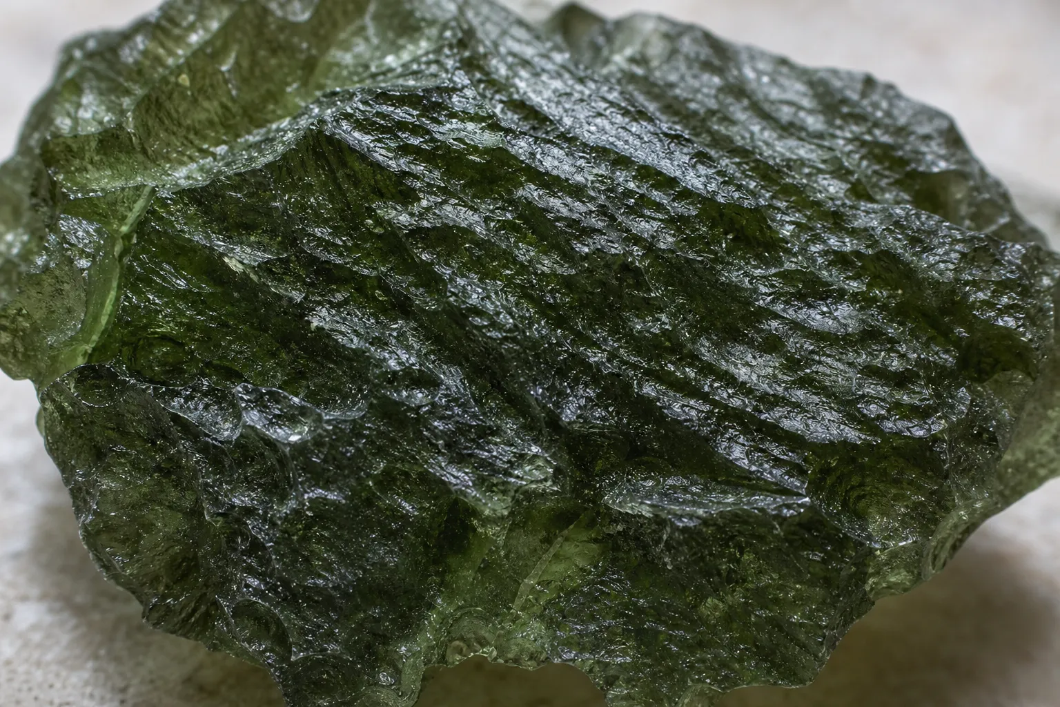 A sharply sculptured green moldavite surface showing ridges, grooves, and prickly relief without treating the texture as proof of locality
