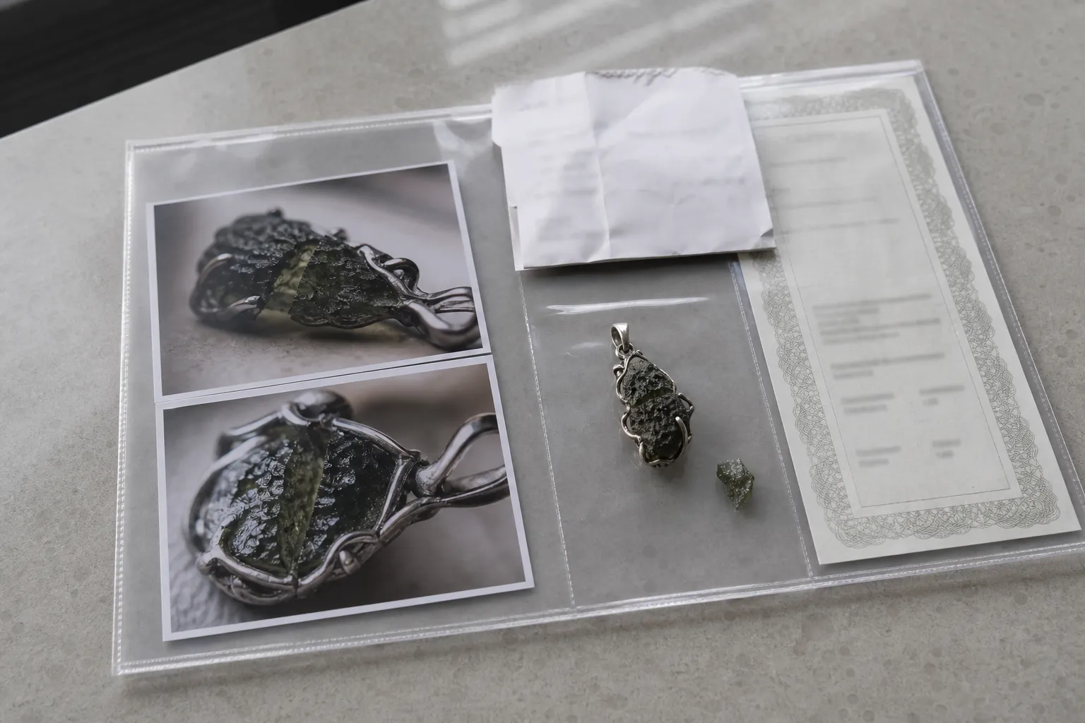 Damaged moldavite jewelry with photos, receipt, and certificate kept together